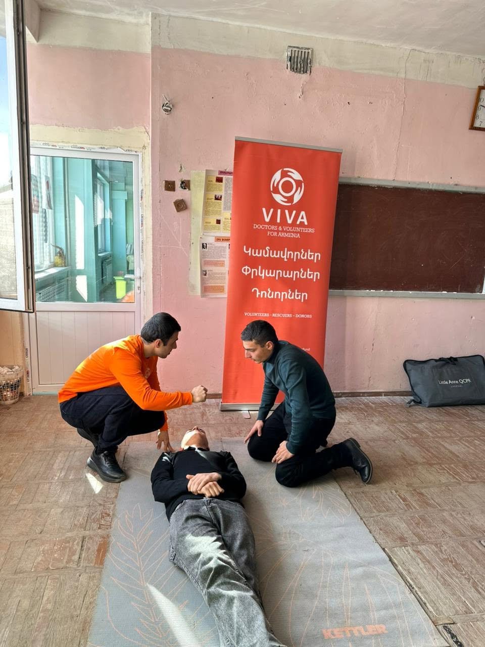 VIVA Foundation instructor in an orange shirt teaching first aid to students at a school in Armenia